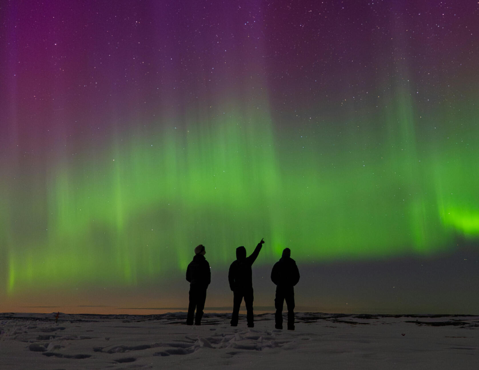 Bucket list adventure Three travelers taking in the Northern Lights in Tromso, Norway